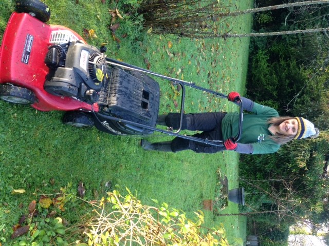An Age UK Cornwall gardener mows the lawn. 