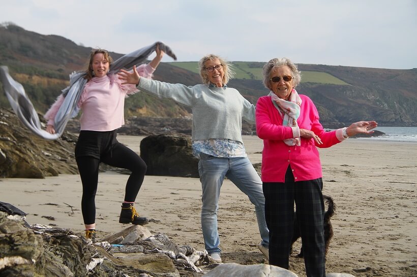 Care team and older woman on a beach, posing for a picture.